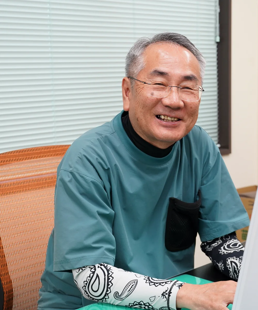 事務所で笑顔を見せる代表社員 久保明